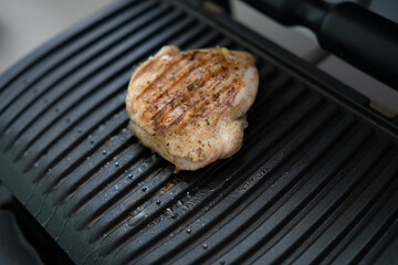 Grilled chicken fillet cooked on the balcony on an electric grill. Fried meat and boiling fat
