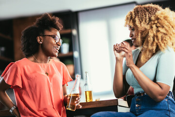 Beautiful young people in casual clothes having fun with bottles of drink, talking and smiling