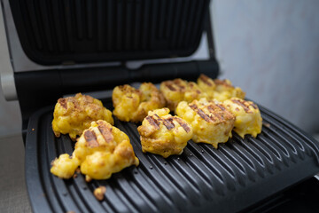 Cauliflower fried in an egg on an electric grill