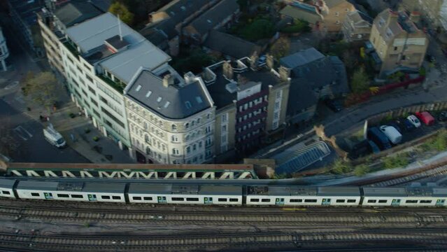 Cinematic aerial tracking shot of train moving through London on its way to the station