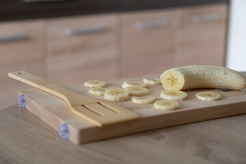 Sliced banana on a wooden board. Healthy food, cooking process in the kitchen