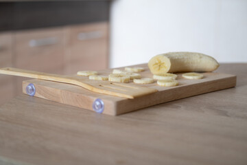 Fototapeta na wymiar Sliced banana on a wooden board. Healthy food, cooking process in the kitchen