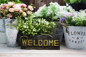 Welcome sign with alarm clock and artificial plant home decoration on wooden background