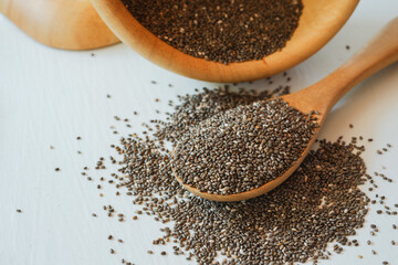 Chia seeds stack and spoon with wooden bowl on white background.