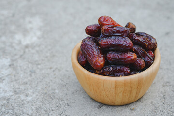 Dates in a wooden cup on a cement floor are high-energy fruits. Muslims eat it during the month of Ramadan.