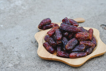 Dates in a wooden cup on a cement floor are high-energy fruits. Muslims eat it during the month of Ramadan.