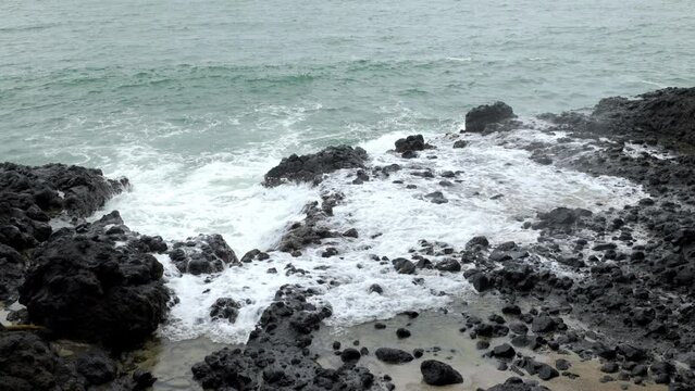 Waves crashing with great force against the rocks raising the water a lot