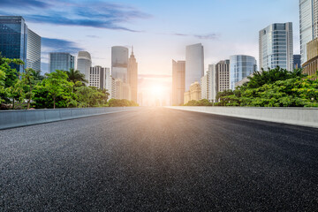 Straight asphalt road and modern city skyline with buildings in Guangzhou at sunset, China.