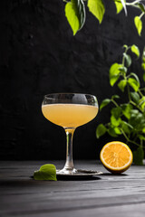 Gold rush sour cocktail with bourbon or whisky, lemon juice and honey sirup served in a coupe glass on dark background