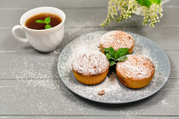 Cupcakes with raisins and a cup of tea, on a background of white flowers.