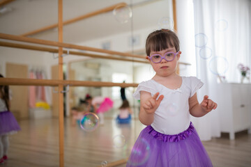 Little girl with down syndrome at ballet class in dance studio. Concept of integration and...