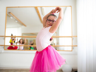 Little girl with down syndrome at ballet class in dance studio. Concept of integration and education of disabled children.