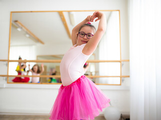 Little girl with down syndrome at ballet class in dance studio. Concept of integration and...
