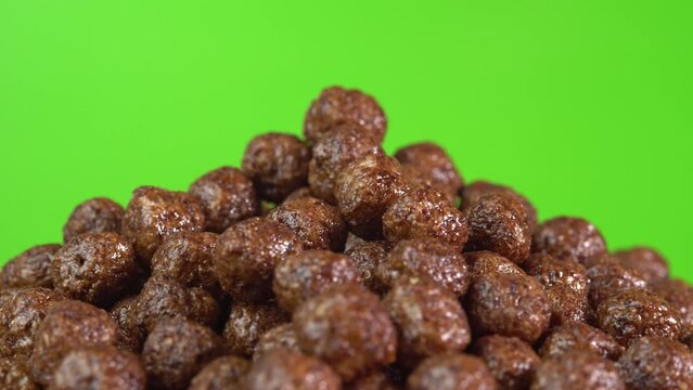 Chocolate cereals rotate on freen background. A healthy breakfast spinning in glass. Making cereals chocolate breakfast tasty healthy. Cereals and cereal products flakes pour in a bowl.