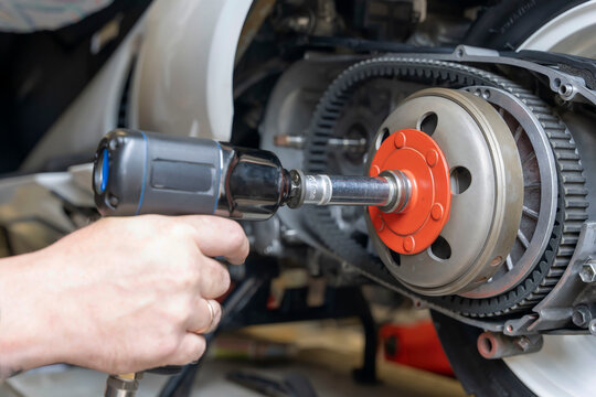 master's hand unscrews the torque driver nut on the scooter variator