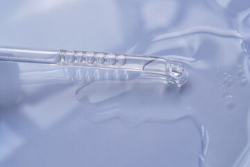 Dropper with serum or cosmetic oil on a blue background.