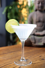 Margarita cocktail in a martini glass with salt rim, decorated with lime, selective focus, with blurred background.