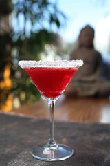 Red cocktail in martini glass with shredded coconut rim, selective focus, with blurred background....