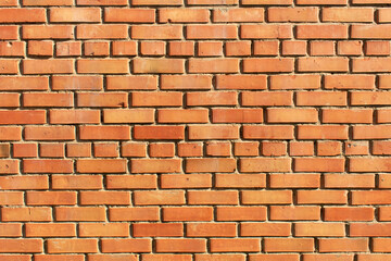 A wall of old, cracked bricks, with a weathered and faded surface. Restored brickwork of an old...