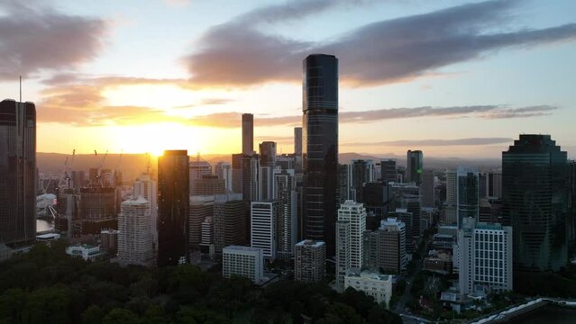 Aerial shot of Brisbane CBD, taken during sunset, golden hour shot, with skyscrapers standing above incredible sky. With Brisbane Botanical Gardens and river in shot as well.