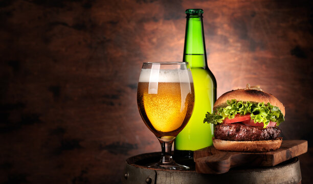 Draft beer glass and hamburger on wooden barrel