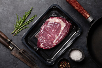 Vacuum packed beef steak. Ribeye steak and cooking utensils