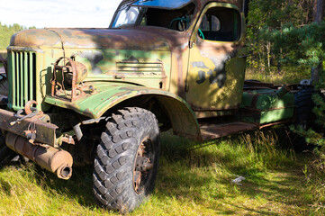 An old large truck with a rusty cab and broken windows