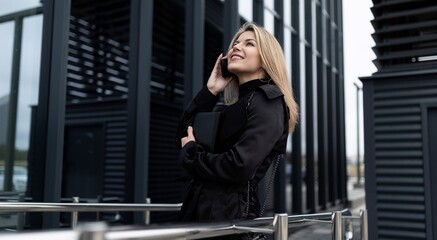 successful business woman speaks on a mobile phone against the backdrop of an office building