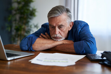 Senior man leaning at the table with financial problems
