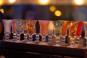 Glass stacks are filled with different drinks as an advertisement in a drinking establishment, a bar on the street