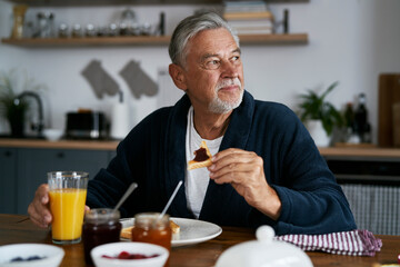 Fototapeta na wymiar Senior caucasian man eating breakfast at home