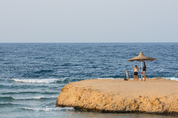 Fototapeta na wymiar family under a single beach umbrella on a bay at the sea in egypt detail