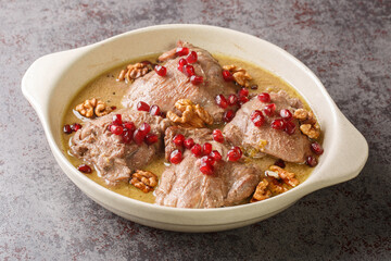 Fesenjan is a simple slowly cooked Iranian stew featuring ground walnuts, pomegranate molasses and chicken thighs close-up in a pan on the table. Horizontal