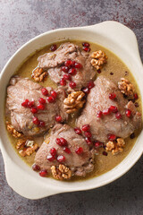 Fesenjan Persian pomegranate walnuts and Chicken Stew close-up in a plate on the table. Vertical top view from above