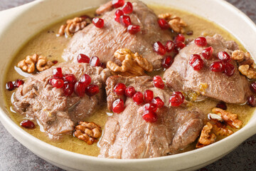 Khoreh Fesenjan tender chicken is cooked in a walnut pomegranate sauce close-up in a pan on the table. Horizontal