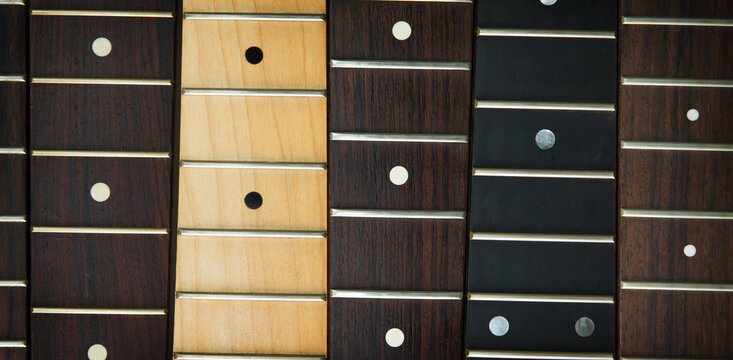 Guitar necks aligned, fretted rosewood, maple and ebony fingerboard necks with round dots for position marker.