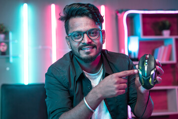 Gamer by looking camera explaining or reviewing new gaming mouse at home - concpet of social media influencer, live commerce and commercial.