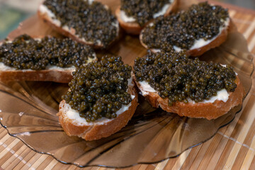 Sandwich with black caviar on wooden background