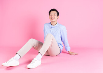 Young Asian man sitting on background