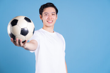Young Asian man holding ball on background - Powered by Adobe