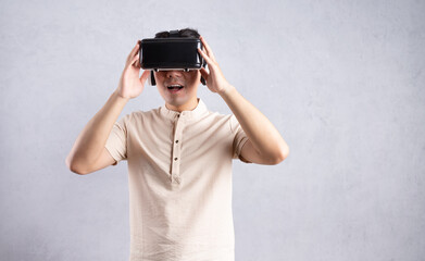 Young Asian man using VR glasses on background