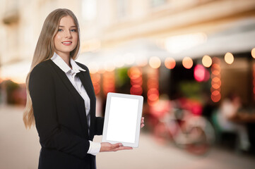 Fototapeta premium Portrait of hostess in uniform with tablet and blurred view of cafe with outdoor terrace. Space for text