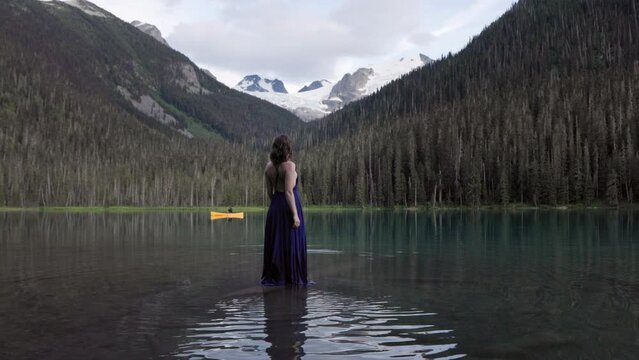 Canadian forest mountain lake, emerald lake, evergreen forest, canoe, young woman in dress, artistic, dreamlike scene. 4K PRORES 24FPS