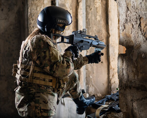 A woman in an army uniform shoots a firearm in an abandoned building. 