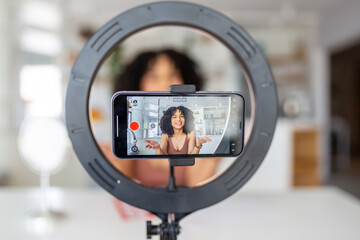 Young female influencer using her smart phone for filming a vlog post.