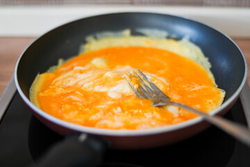 scrambled eggs in a pan on the stove, mixed with a fork