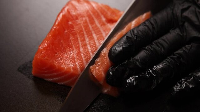 Chef slicing salmon close up. Raw fish on cutting board.