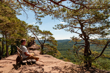 Man sitting on top of a rock enjoying the landscape