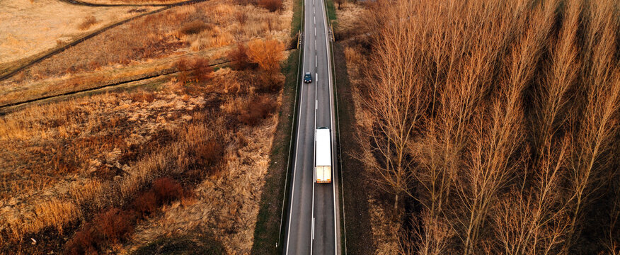 Aerial Shot Of Semi Truck And Car Driving Along The Highway Through Autumn Scenery Landscape, Drone Pov