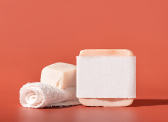 Handmade soap bars with blank label and small towel on pink close up, hard shadows